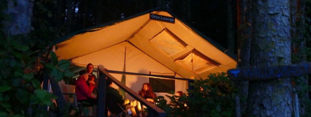 two people standing outside of a tent at night