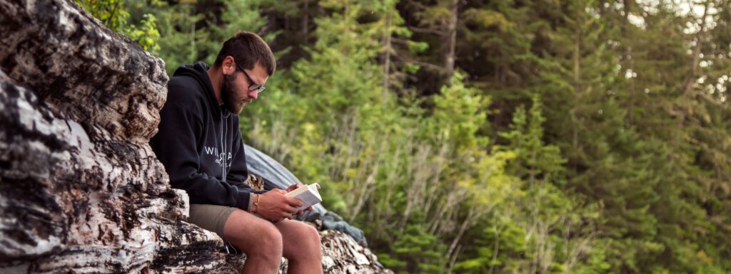 a man sitting on a rock looking at his cell phone