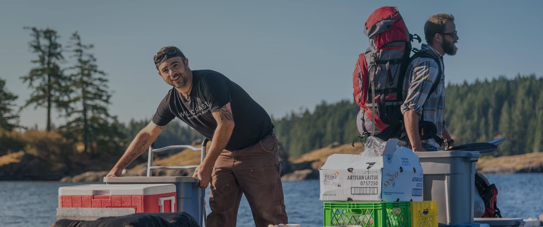 two men standing on a boat with their dogs