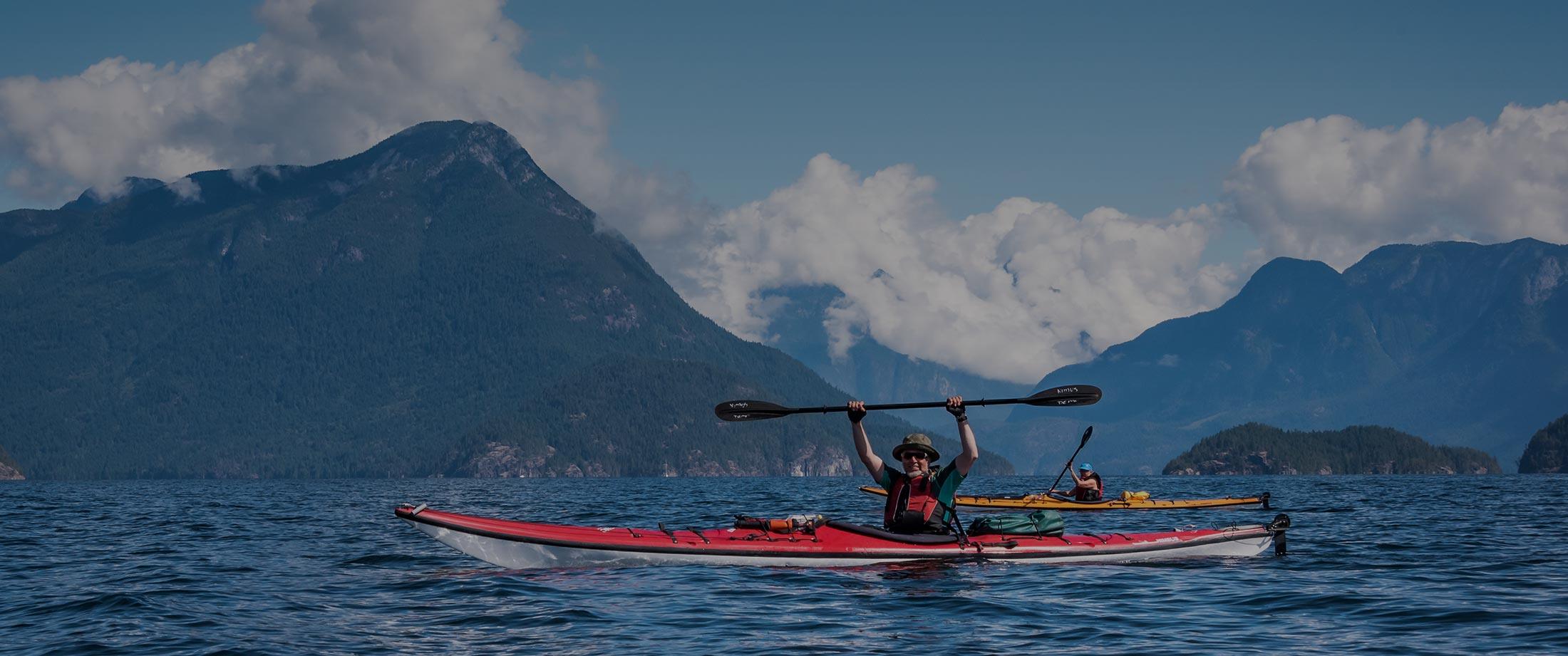 two people in kayaks paddling on the water