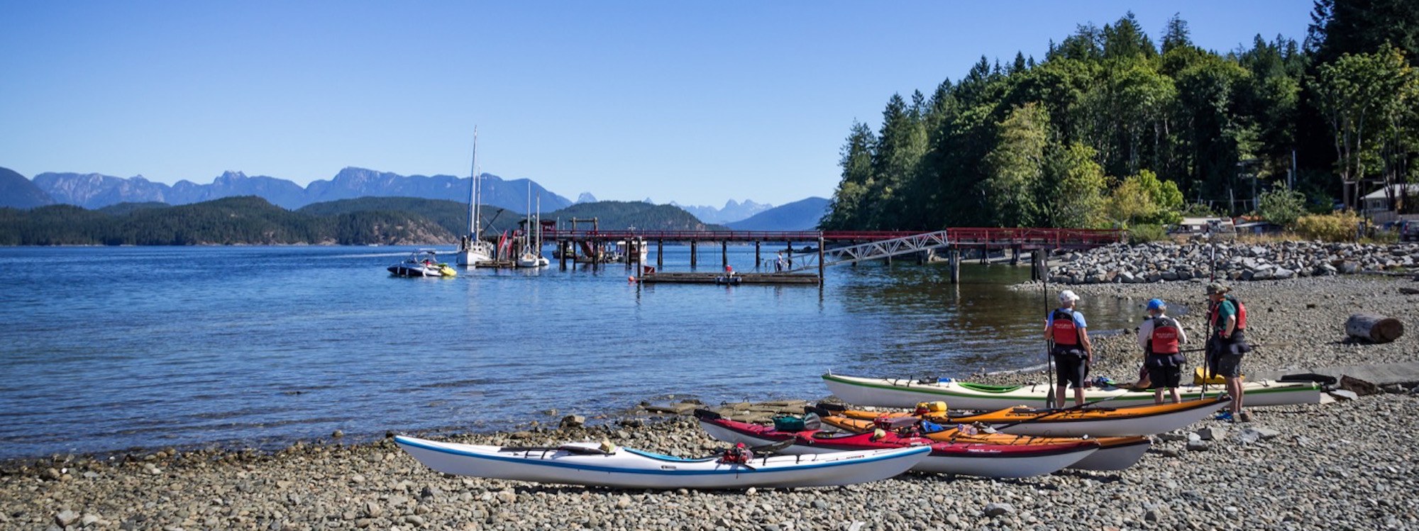 three canoes are on the shore of a lake