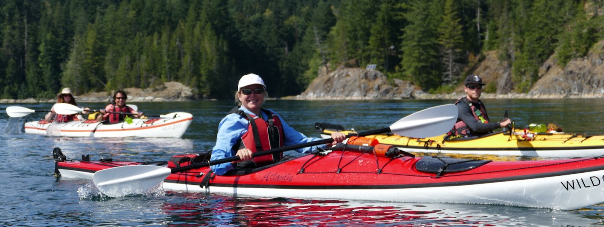 a group of people riding on top of kayaks in the water