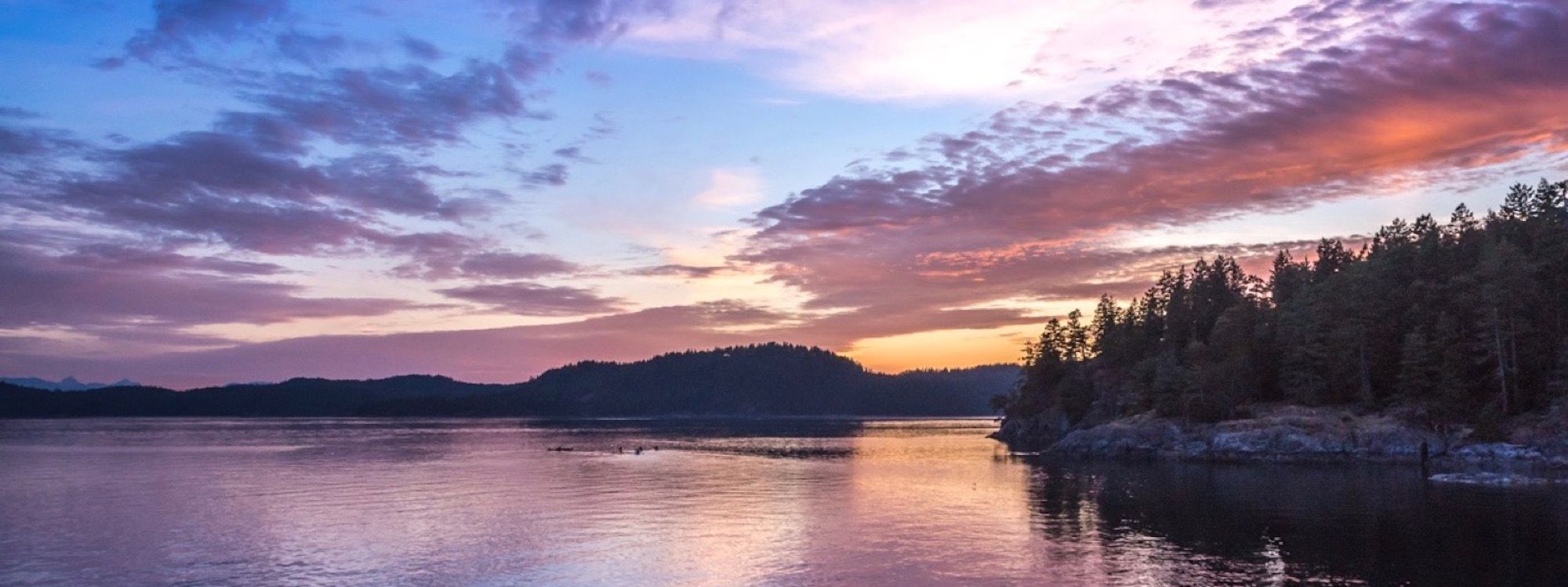 a beautiful sunset over a lake with trees