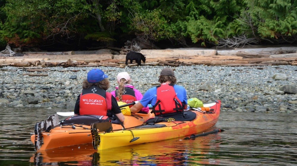 three people in an orange kayak on the water