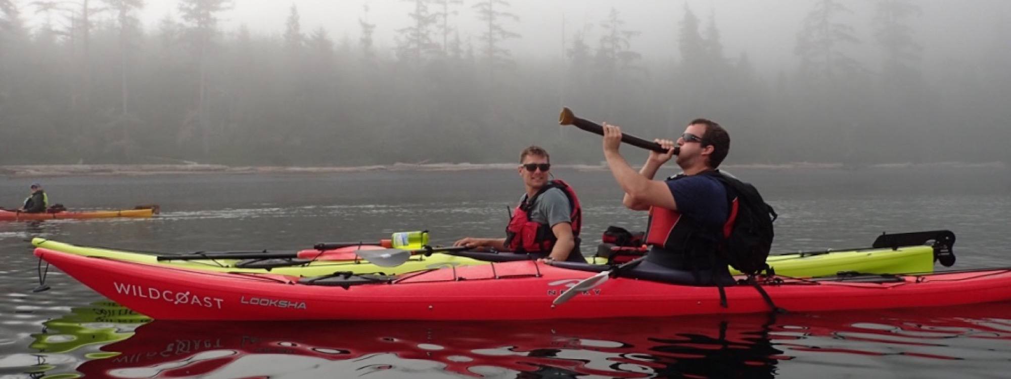 two men in red kayaks paddling on the water