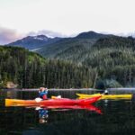 two people in kayaks paddling on a lake