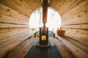 Interior of cedar sauna, wood fire burning. Stainless chimney