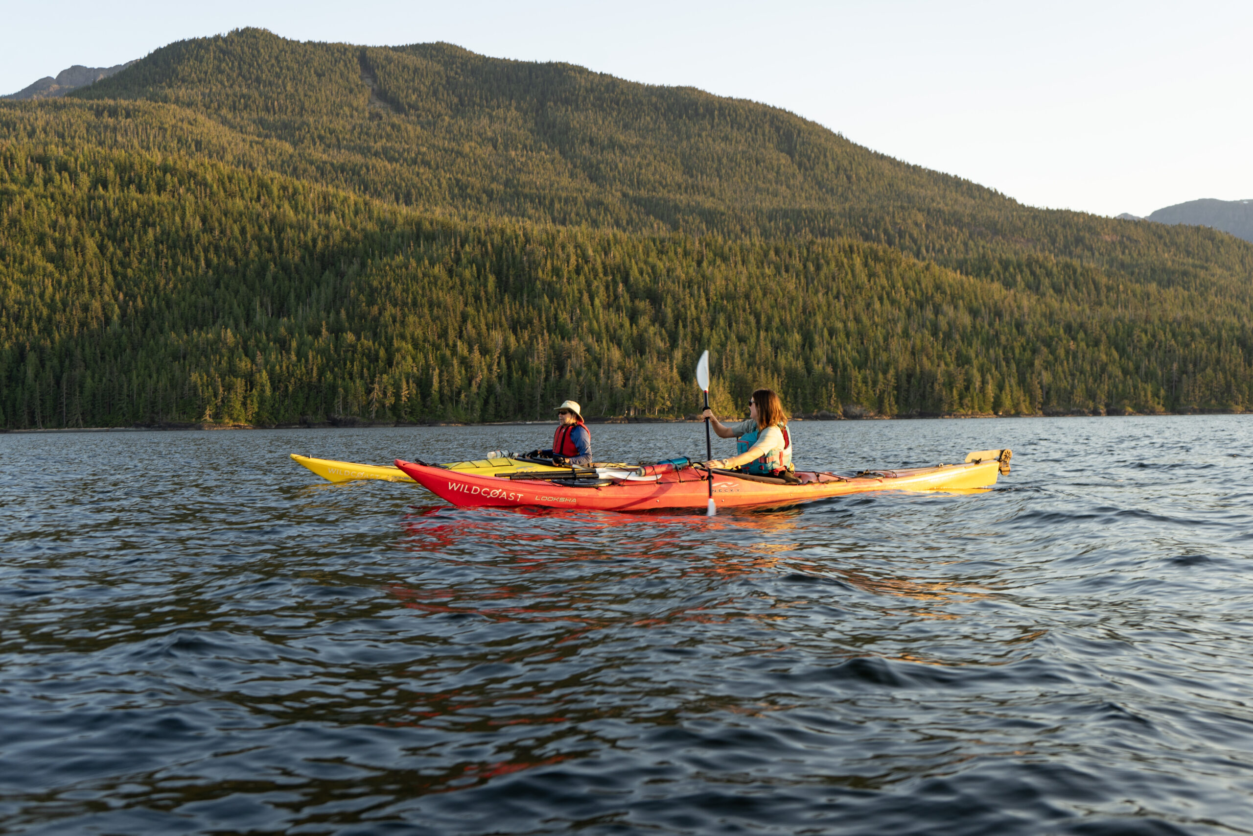 two kayakers paddling on the ocean at sunset
