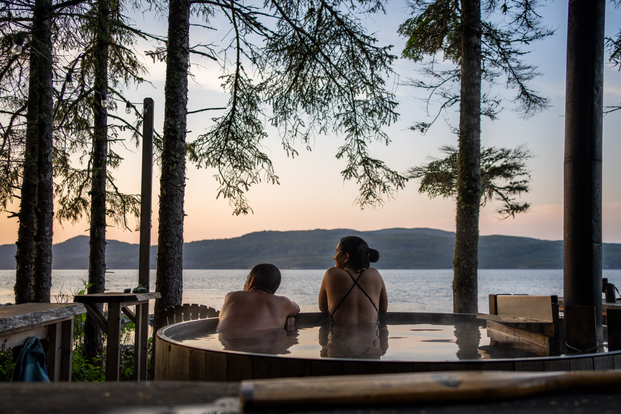 Two guests enjoying the hot tub with ocean view at Orca Camp