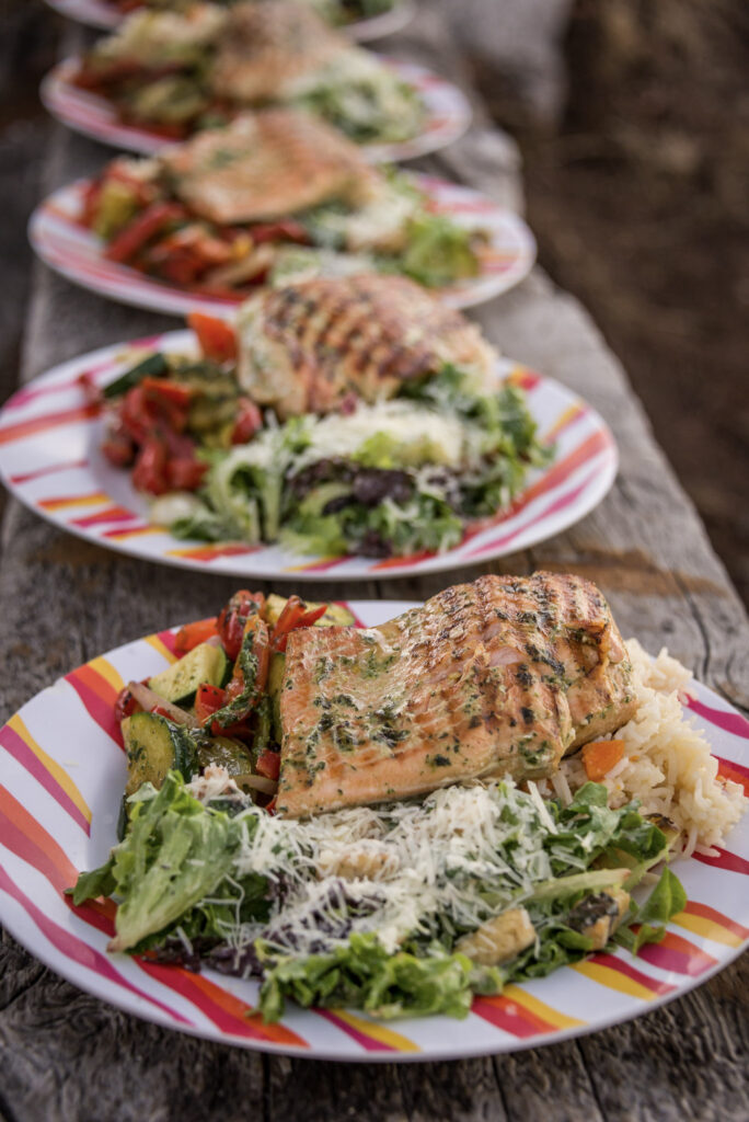 Grilled salmon, rice and fresh salad served for dinner at camp