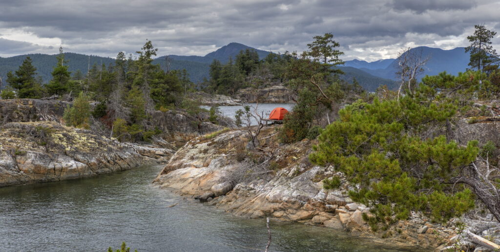 Orange tent pitched on a rocky granite shoreline in Desolation Sound