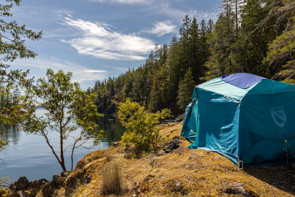 Tent on a grassy bluff above the water at a Discovery Islands campsite