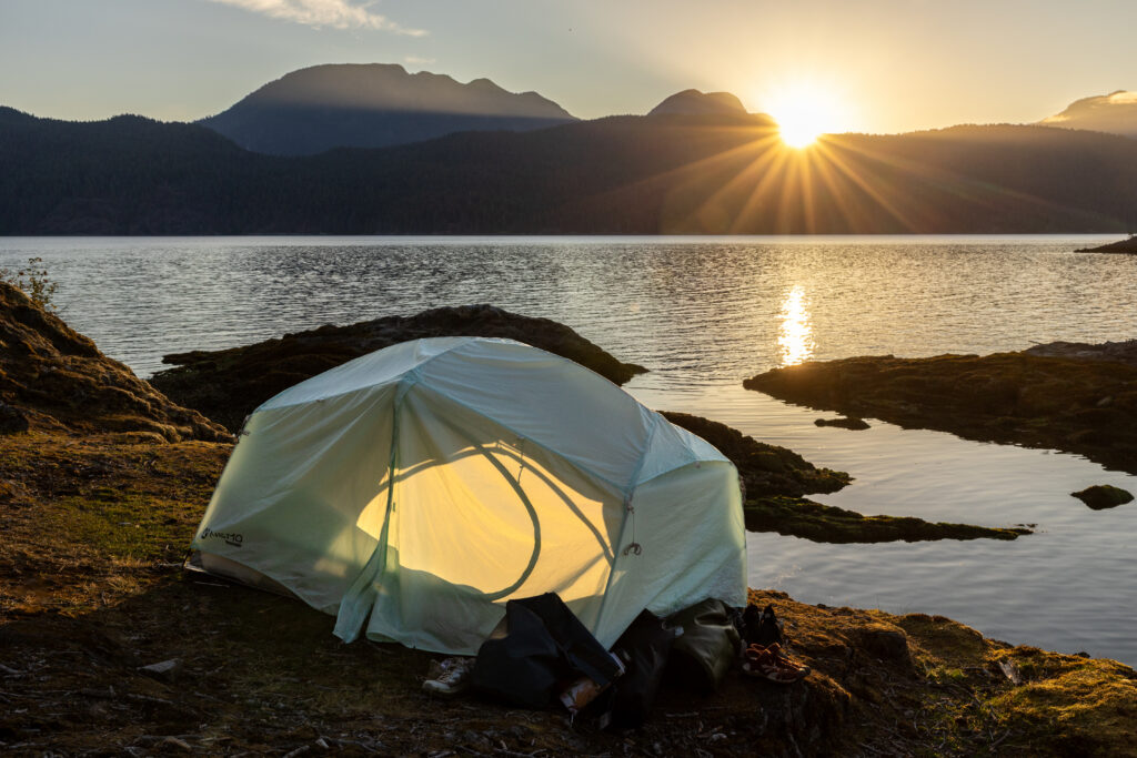 Tent glowing at sunset on a rocky point in the Discovery Islands