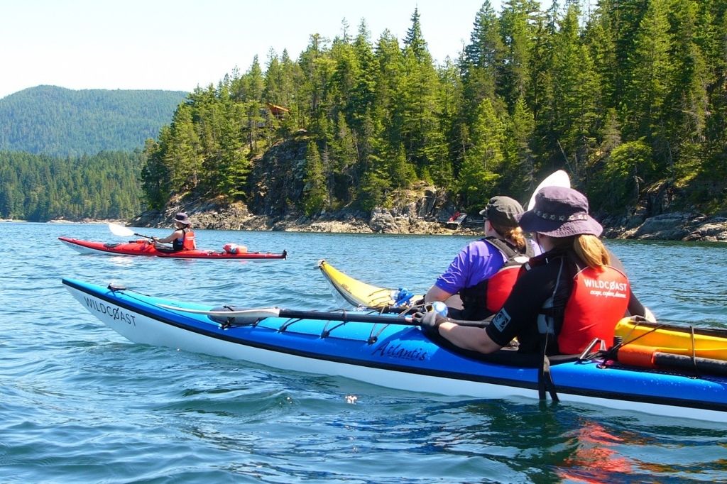 three people in kayaks paddling on the water