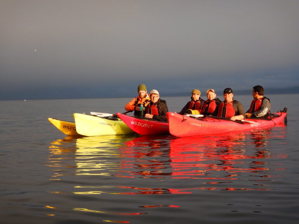 a group of people riding on top of kayaks in the water